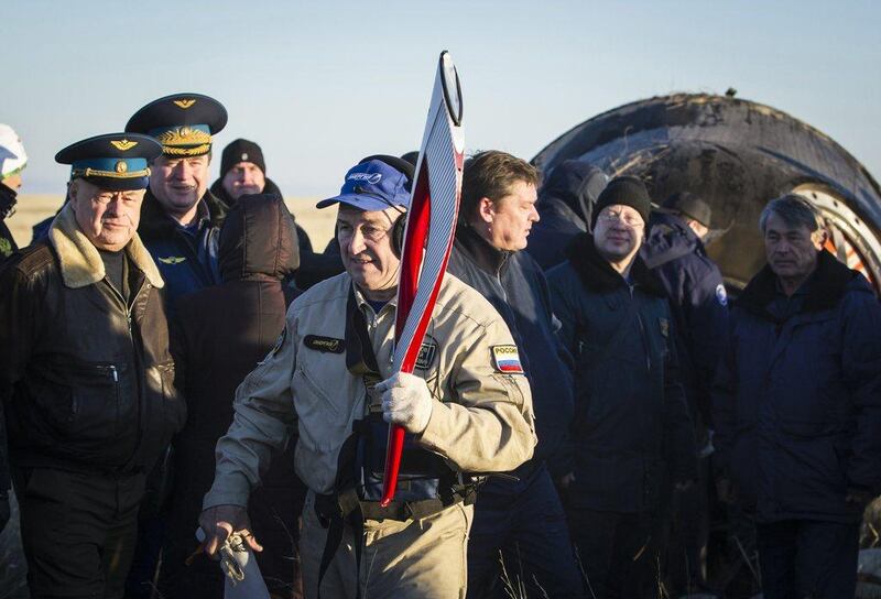 A ground crew member carries a torch of the 2014 Sochi Winter Olympic Games delivered from orbit in the Soyuz TMA-09M capsule after its landing in a remote area near the town of Zhezkazgan in central Kazakhstan. Shamil Zhumatov / AP Photo