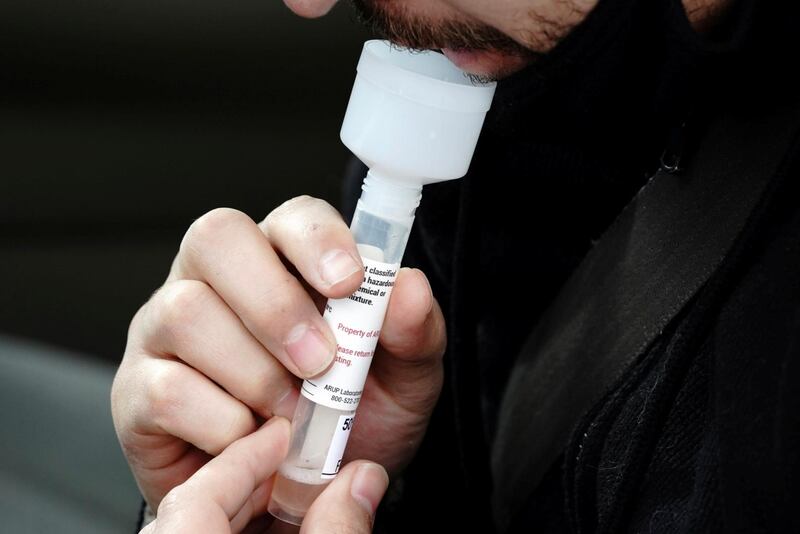 A patient collects his own saliva sample at a drive-thru COVID-19 testing site operated by University of Utah Health at Rice-Eccles Stadium, as the coronavirus disease (COVID-19) outbreak continues in Salt Lake City, Utah, U.S., November 14, 2020. REUTERS/Bing Guan