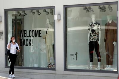 A woman wearing a mask walks past a storefront window reading 'Welcome Back', along Makarios Avenue, a busy shopping street in Cyprus' capital Nicosia, on Monday, May 4, 2020. Retail shops were opened Monday, the first day of the gradual rolling back of a strict stay-at-home order that was enacted in late March to arrest the spread of the coronavirus. (AP Photo/Petros Karadjias)