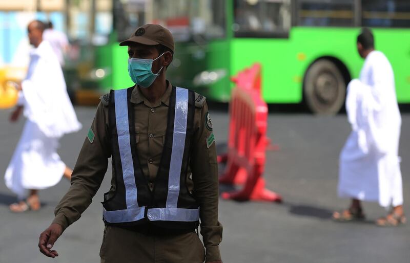 A masked Saudi police officer stands in a street outside the Grand Mosque. AFP