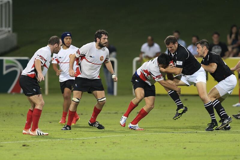 UAE rugby player Daniel Minks pushes against a Singapore tackler during Wednesday night’s Asian Five Nations Test. Sarah Dea / The National / April 23, 2014 