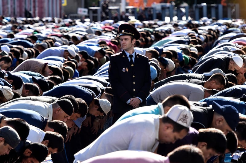A police officer stands among Russian Muslims praying outside the central mosque in Moscow on July 5, 2016, during celebrations of Eid al-Fitr marking the end of the fasting month of Ramadan. / AFP PHOTO / KIRILL KUDRYAVTSEV