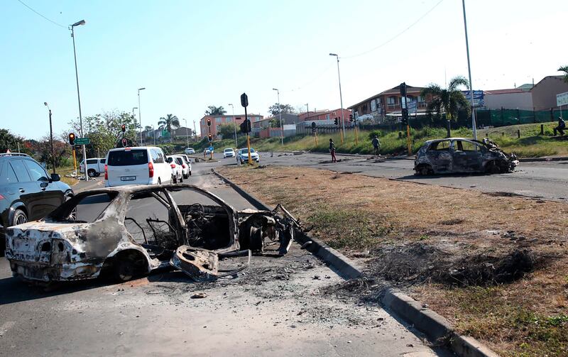 A burnt out vehicle alongside a road in Phoenix, near Durban, South Africa, Friday, July 16, 2021, after violence in the town.  South Africa's army has begun deploying 25,000 troops to assist police in quelling weeklong riots and violence sparked by the imprisonment of former President Jacob Zuma.