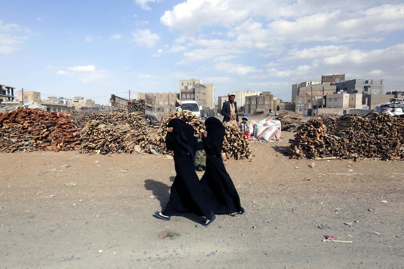 Two Yemeni women walk past firewood displayed for sale amid an ongoing cooking gas shortage in Sana'a, Yemen. Yahya Arhab / EPA