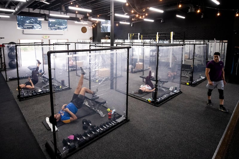 epa08503091 Peet (R) trains his students surrounded by plastic sheets to ensure social distancing at the Inspire South Bay Fitness gym amid the coronavirus pandemic in Redondo Beach, California.  EPA