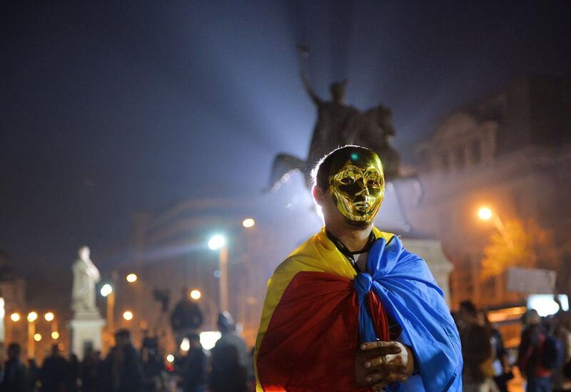 A protestor wears a golden mask and Romanian flag during a demonstration in Bucharest against the Rosia Montana Gold Corporation (RMGC), a Canadian gold mine project using cyanide,in Bucharest on November 3, 2013. People around Romania took to the streets again to protest plans by a Canadian company to open Europe’s largest goldmine in a Transylvanian village. Canadian company Gabriel Resources hopes to extract 300 tons of gold using thousands of tons of cyanide in Rosia Montana, a picturesque village in the Carpathian mountains. The government recently adopted a bill clearing the way for the open cast mine.  Daniel Mihailescu  / AFP photo