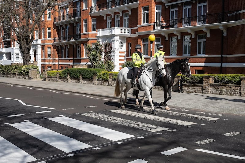 LONDON, ENGLAND - MARCH 24: Two mounted police officers ride their horses across the iconic Abbey Road crossing as a Highways Maintenance team take advantage of the COVID-19 coronavirus lockdown and quiet streets to refresh the markings on March 24, 2020 in London, England. The Beatles made the pedestrian crossing famous after featuring a photograph of the group walking on it, near to Abbey Road Studios. The album and connected artwork celebrated its fiftieth anniversary last year. British Prime Minister, Boris Johnson, announced strict lockdown measures urging people to stay at home and only leave the house for basic food shopping, exercise once a day and essential travel to and from work. The Coronavirus (COVID-19) pandemic has spread to at least 182 countries, claiming over 10,000 lives and infecting hundreds of thousands more. (Photo by Leon Neal/Getty Images)