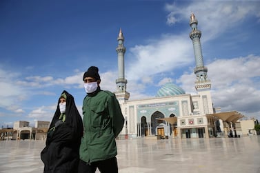 A couple wearing protective face masks, following the outbreak of Covid-19, walks on the street in Qom, Iran March 24, 2020. West Asia News Agency via Reuters