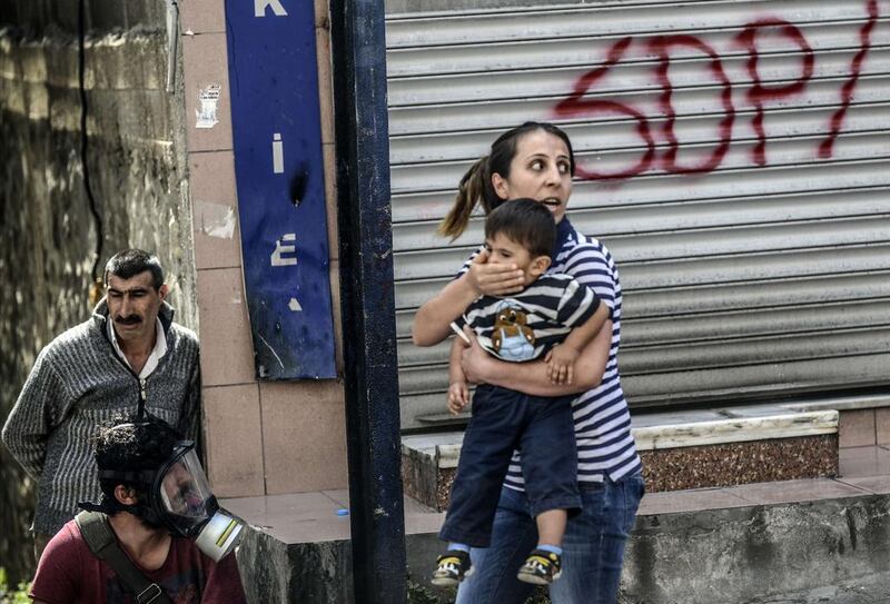 A woman holds her child as she tries to make her way through a street during clashes between Turkish riot police and protesters taking part in a demonstration against the recent mine accident in Soma. Bulent Kilic / AFP Photo