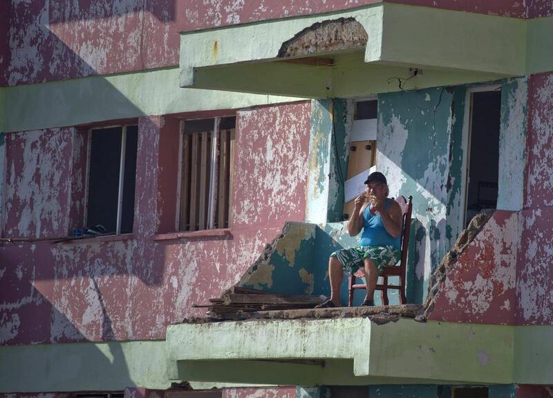 A man eats a piece of chicken while sitting on his balcony that was damaged by Hurricane Matthew, in Baracoa, Cuba. Ramon Espinosa / AP Photo