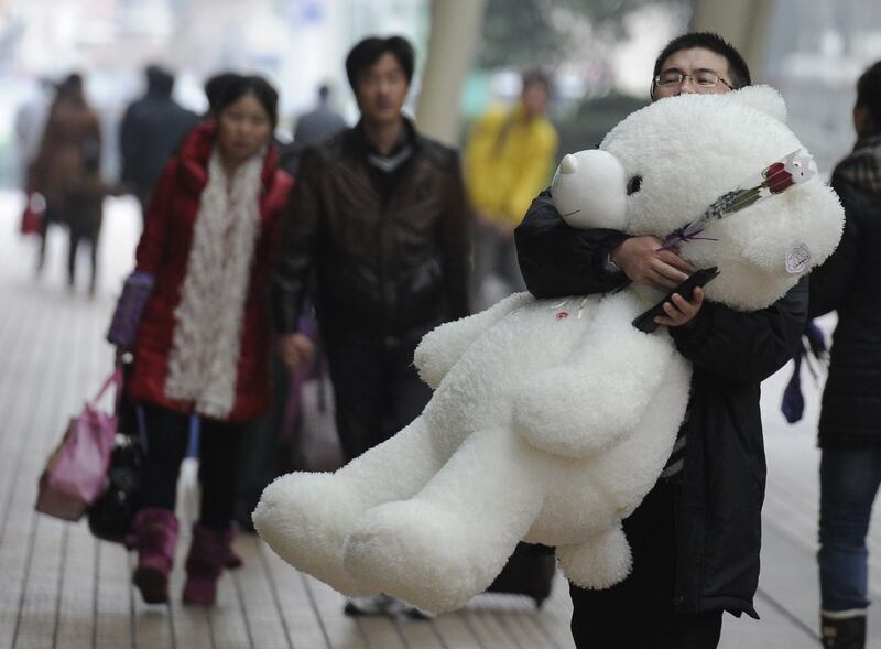 A man carries a large teddy bear and a rose on a street in Shanghai on February 14, 2012.  Valentine's Day is a holiday observed on February 14 honoring one or more early Christian martyrs named Saint Valentine. It was first established by Pope Gelasius I in 496 AD, and was later deleted from the General Roman Calendar of saints in 1969 by Pope Paul VI.  AFP PHOTO/Peter PARKS
 *** Local Caption ***  864064-01-08.jpg