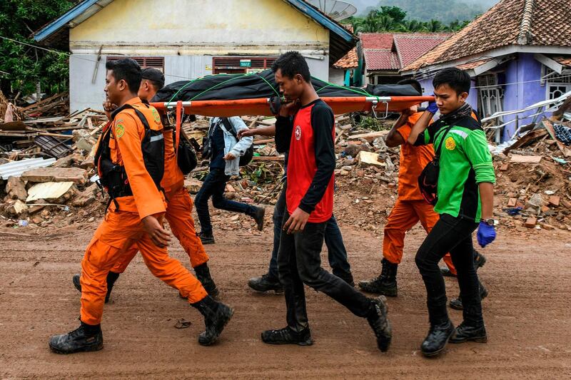 Members of an Indonesian search and rescue team carry the body of a victim, retrieved from a collapsed home, in a body bag in Rajabasa. AFP