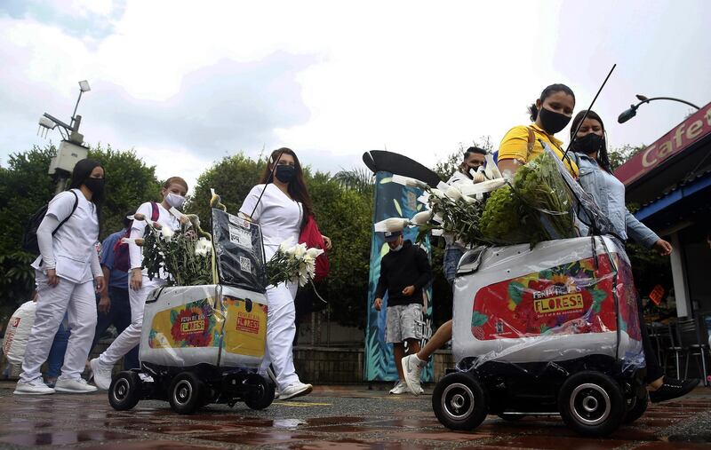 People look at robots distributing flowers during a flower fair in Medellin, Colombia. EPA