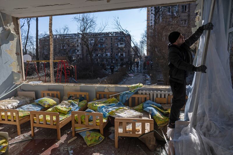 A man removes a curtain inside a school in Kyiv. AP