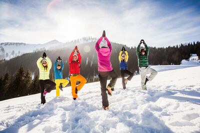 Group of friends doing yoga in snow