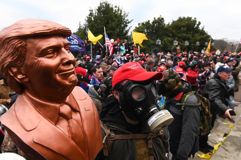 A supporter of Donald Trump wears a gas mask and holds a bust of him after he and hundreds of others stormed stormed the Capitol building on January 6, 2021 in Washington AFP
