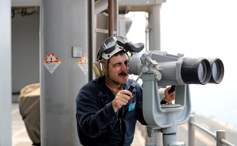 A US Navy officer uses binoculars to follow the movements near the USS Boxer.
