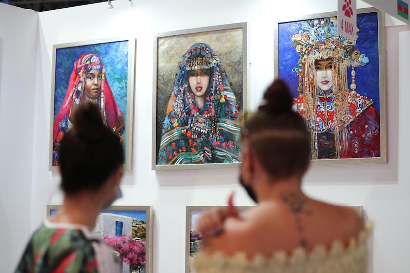 Visitors look at artworks presented by the Nargiz Art Studio from Azerbaijan. EPA