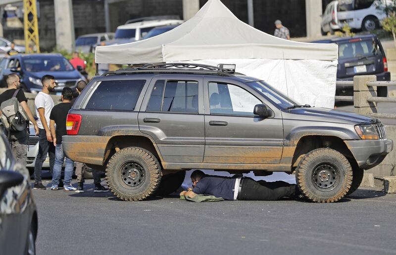 A Lebanese protester rests under a vehicle blocking a highway in the town of Zouk Mosbeh during ongoing anti-government demonstrations. AFP