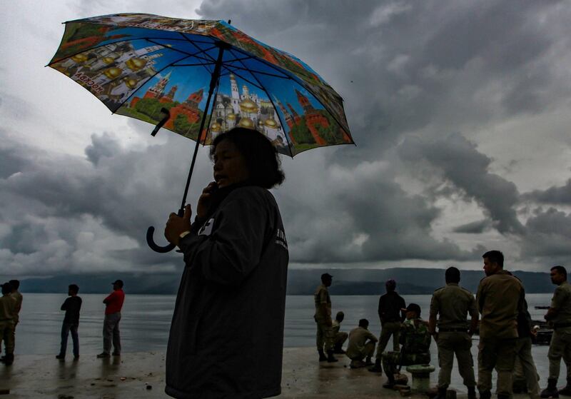 A woman speaks on a phone while waiting for rescue teams to find her missing family members from a capsized ferry at Lake Toba, in North Sumatra province, Indonesia. Rahmad Suryadi / AFP