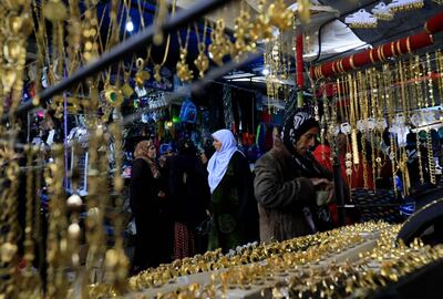 Women walk in front of shops selling golden jewelry at a market street in the northeastern Syrian town of Qamishli on May 2, 2018.  Many Kurds in Syria may dream of self-rule, but for business owners in the semi-autonomous region in the country's north, it now comes with a painful pinch: double taxes paid both to Kurdish authorities and the central government in Damascus.  / AFP / Delil souleiman
