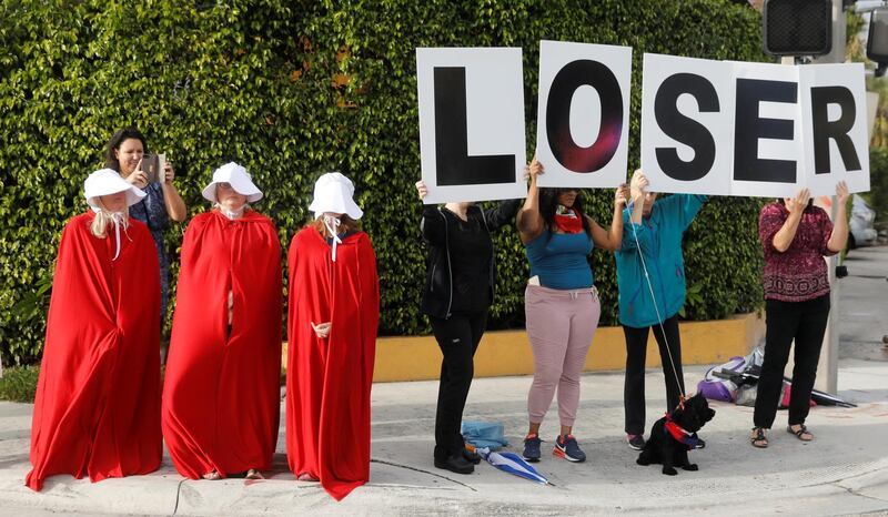Anti-Trump demonstrators hold signs as the motorcade of U.S. President Donald Trump passes in West Palm Beach, Florida, U.S., January 15, 2018.  REUTERS/Kevin Lamarque