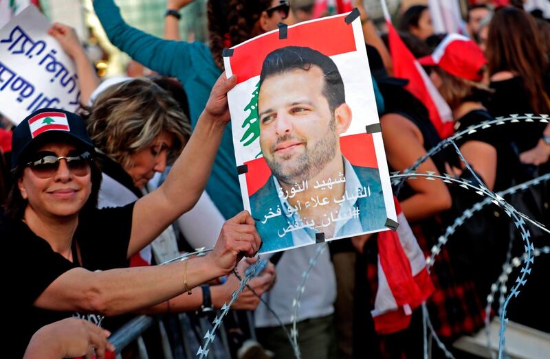 A Lebanese demonstrator carries a portrait of Alaa Abou Fakhr, who was shot dead south of Beirut the day before, during a gathering on the road leading to the Presidential Palace in Baabda, on the eastern outskirts of Beirut on November 13, 2019, nearly a month into an unprecedented anti-graft street movement. Street protests erupted, the night before, after President Michel Aoun defended the role of his allies, the Shiite movement Hezbollah, in Lebanon's government. Protesters responded by cutting off several major roads in and around Beirut, the northern city of Tripoli and the eastern region of Bekaa. / AFP / ANWAR AMRO
