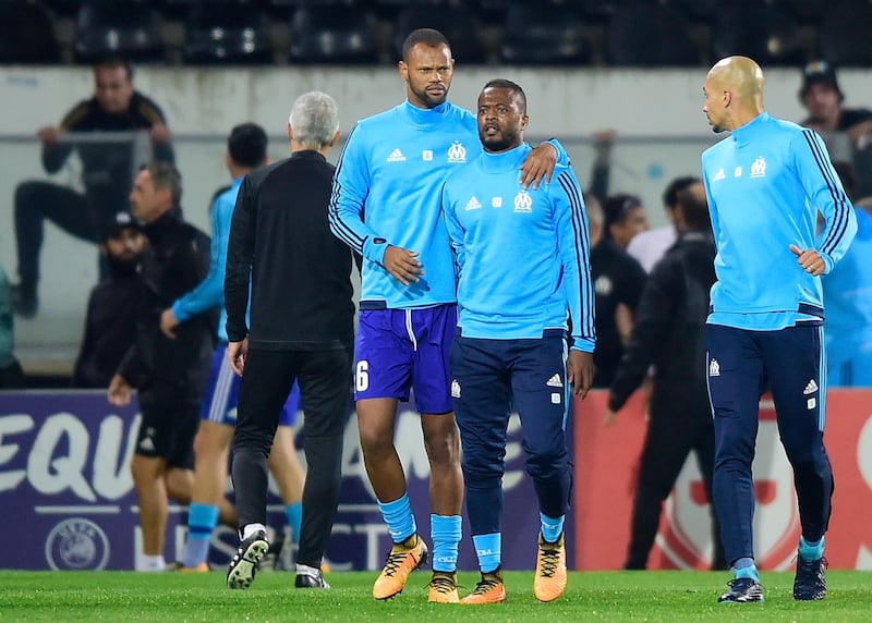 FILE - In this Thursday, Nov. 2, 2017 file photo, Marseille's Patrice Evra, center right, is led away by his teammate Rolando after a scuffle with Marseille supporters who trespassed onto the field before the Europa League group I soccer match between Vitoria SC and Olympique de Marseille at the D. Afonso Henriques stadium in Guimaraes, Portugal. UEFA has suspended Marseille defender Patrice Evra until June 2018 for kicking one his own team's fans before a Europa League game. (AP Photo/Luis Vieira, File)