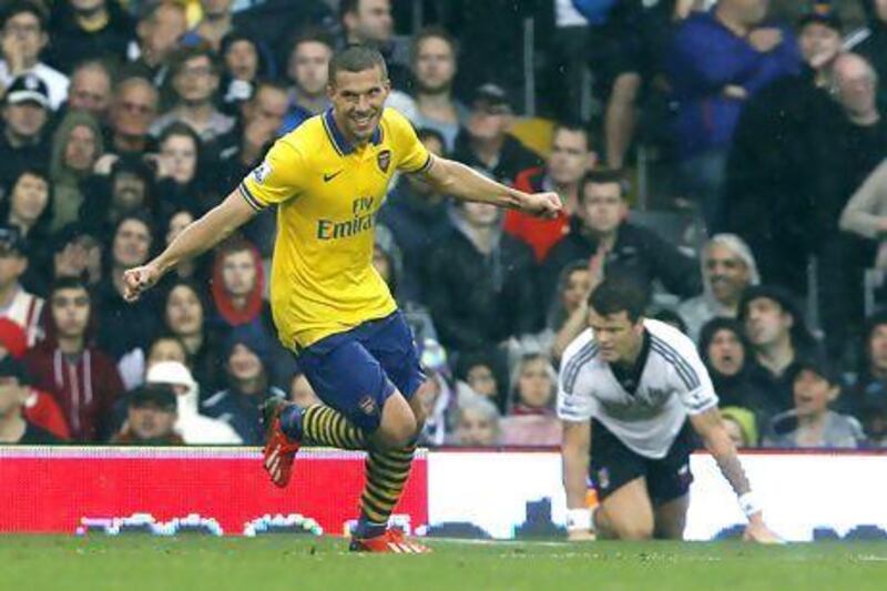 Arsenal's Lukas Podolski, left, celebrates his first goal against Fulham at Craven Cottage. Sang Tan / AP Photo