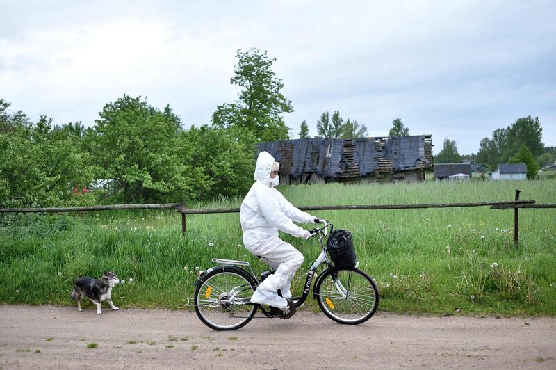 Paramedic Nadezhda Konanava, 65, wearing a protective suit rides her electric bike at the village of Novaya Obol, some 70km outside Vitebsk.  AFP