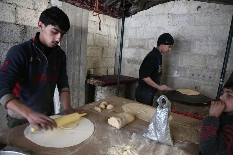 Syrian youth prepare bread as they take shelter inside a building in Haza, in the  besieged Eastern Ghouta region on the outskirts of the capital Damascus on February 27, 2018. - A humanitarian "pause" announced by Russia in Syria's deadly bombardment of Eastern Ghouta struggled to take hold, with fresh violence erupting and no sign of aid deliveries or residents leaving the besieged enclave. (Photo by ABDULMONAM EASSA / AFP)