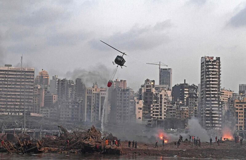 TOPSHOT - A helicopter try to put out multiple fires at the scene of the massive explosion that hit Beirut's port on August 4, 2020 in the heart of the Lebanese capital. Rescuers searched for survivors in Beirut on August 5 after a cataclysmic explosion at the port sowed devastation across entire neighbourhoods, killing more than 100 people, wounding thousands and plunging Lebanon deeper into crisis. / AFP / -
