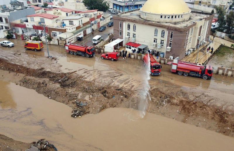 Firefighters pump water from a flooded building.