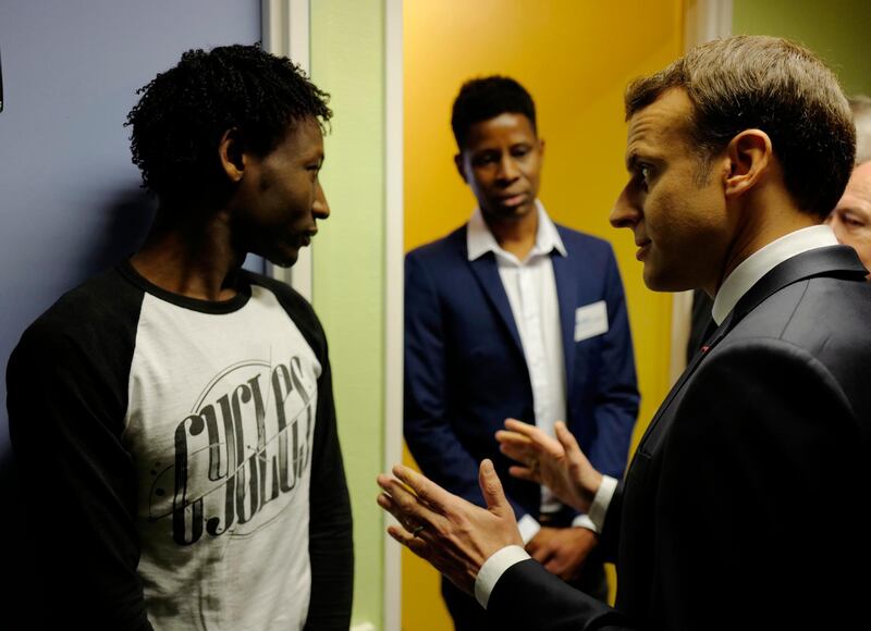 FILE - In this Jan.16, 2018 file photo, Ahmed Adam, left, from Sudan listens to French President Emmanuel Macron in a migrant center in Croisilles, northern France. Macron's government presents its first big immigration bill at Cabinet meeting Wednesday Feb.21, 2018. The government says the bill aims at accelerating expulsion of people who don't qualify for asylum and offering better conditions for those who are allowed to stay in the country. At center is translator Elyas Ali, from Chad. (AP Photo/Michel Spingler, Pool, File)