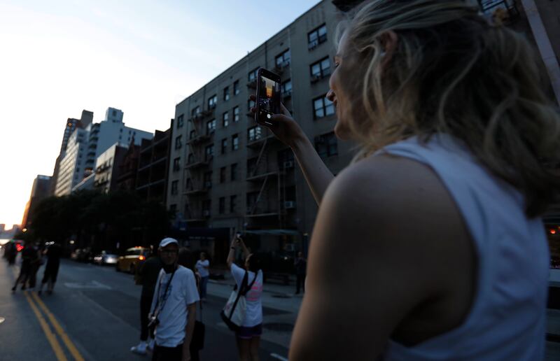 A woman takes a picture on her mobile phone on 57th Street during Manhattanhenge. EPA