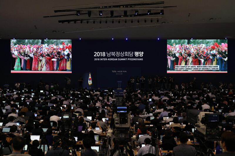 Members of the media watch screens showing a broadcast of Moon Jae-in's arrival. Bloomberg
