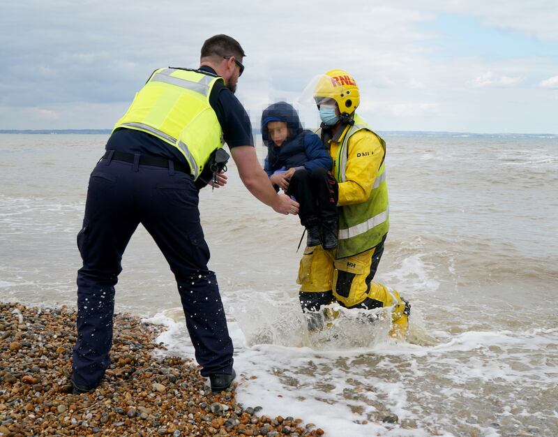 A migrant boy is carried to shore in Dungeness on September 15, 2022. PA