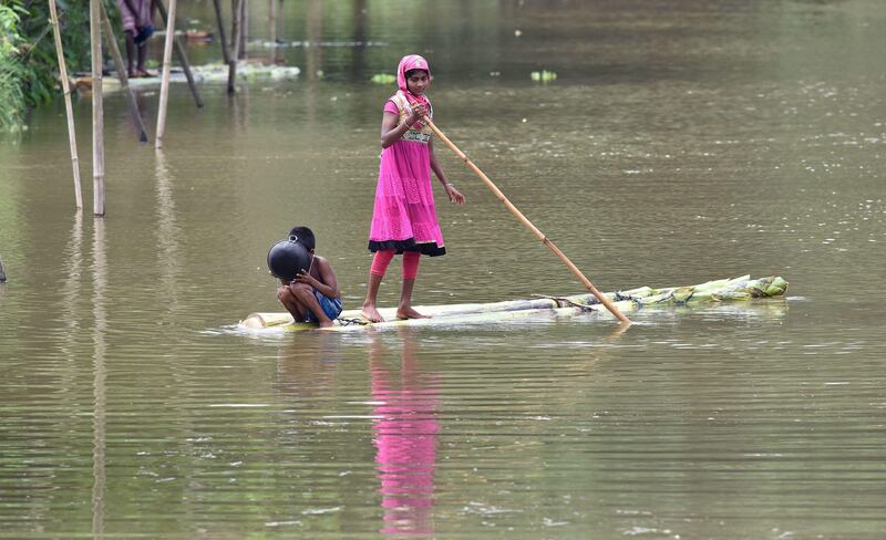 An Indian girl and her brother travel by raft to cross floodwaters in the Assam village of Murkata on July 6, 2017. Biju Boro / AFP