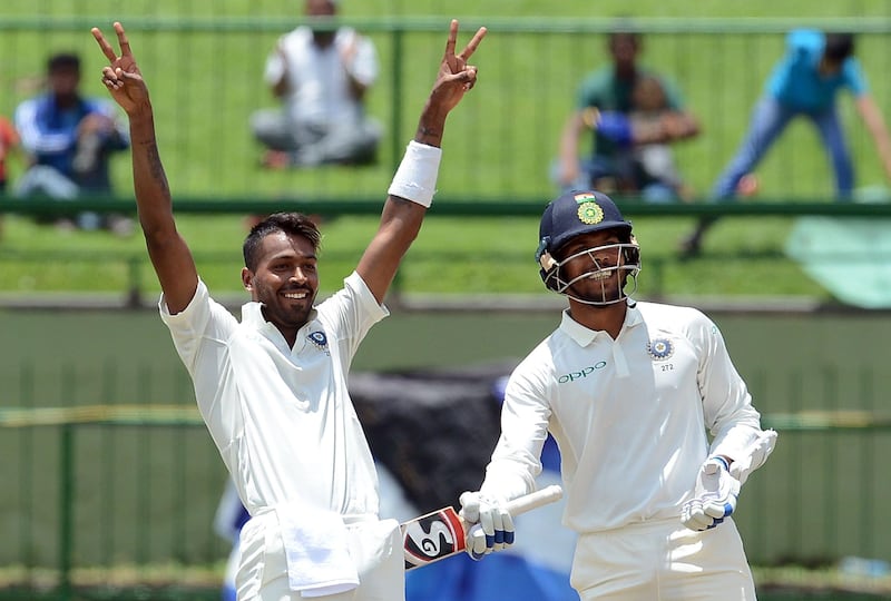 India's Hardik Pandya celebrates after scoring a century as his teammate Umesh Yadav (R) looks on during the second day of the third and final Test match between Sri Lanka and India at the Pallekele International Cricket Stadium in Pallekele on August 13, 2017. / AFP PHOTO / LAKRUWAN WANNIARACHCHI