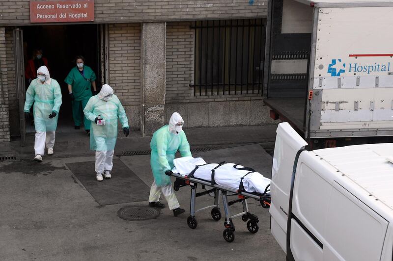 A health worker carries a body on a stretcher outside Gregorio Maranon hospital in Madrid.  AFP