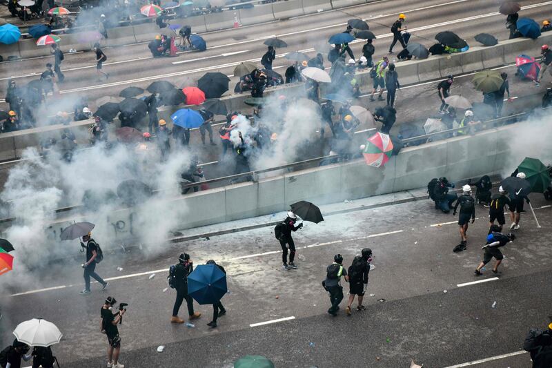 Protesters react after police fired tear near the government headquarters of Hong Kong.   AFP