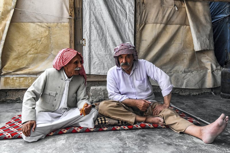 Men sit togther on a futon outside a shelter at a camp for internally displaced persons (IDP) of Iraq's Yazidi minority in the Sharya area, some 15 kilometres from the northern city of Dohuk in the autonomous Iraqi Kurdistan region on August 30, 2019. (Photo by Zaid AL-OBEIDI / AFP)