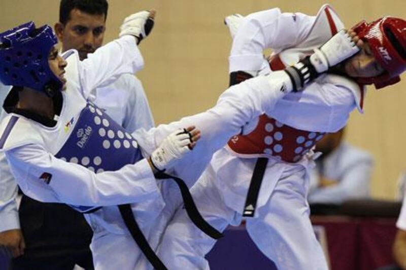 Malek Abrub of Palestine, left, delivers a blow to Yussef Al Otaini of Qatar in a 54kg taekwondo bout during the 2011 Arab Games in Doha.