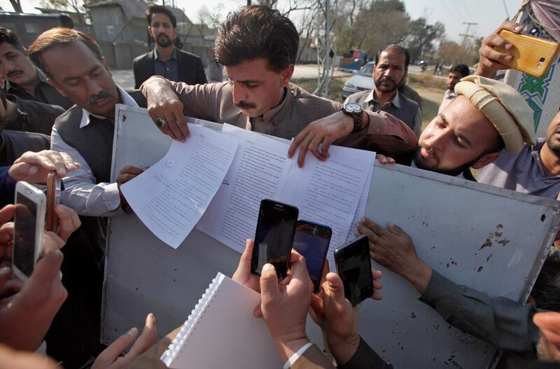 Pakistani journalists film a copy of the verdict in the university student lynching case outside a prison in Haripur, Pakistan, Wednesday, Feb. 7, 2018. A Pakistani court sentenced a man to death and convicted 30 others over the lynching of a 23-year-old university student who was falsely accused of blasphemy, officials said. (AP Photo/Anjum Naveed)