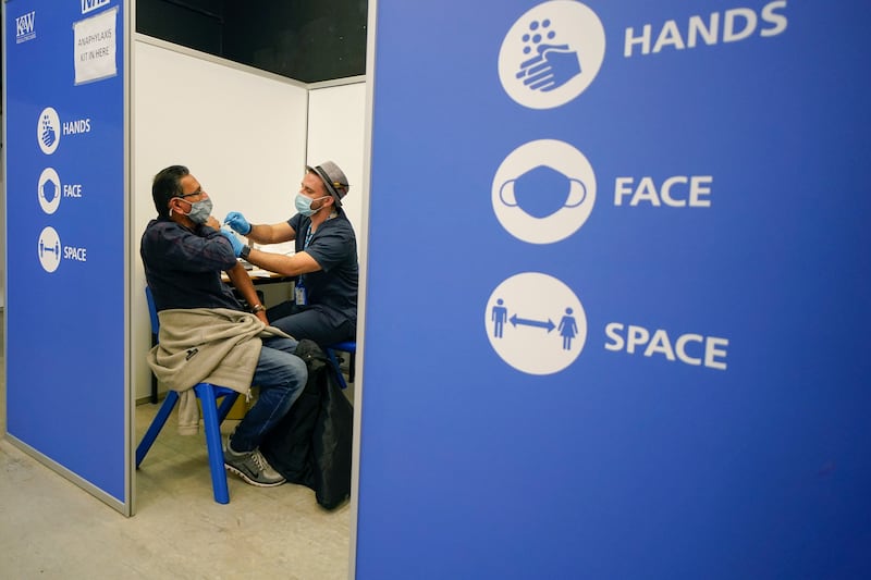 A patient receives the Pfizer vaccine at Swaminarayan School vaccination centre, in London. Britain says it will offer all adults a booster dose of vaccine within two months. AP Photo