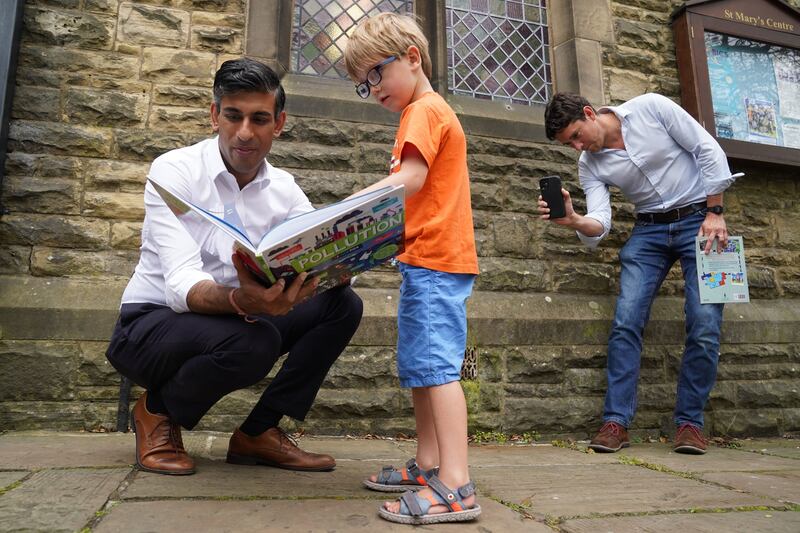 Rishi Sunak looks at a book with Teddy Openshaw, 4, as his father, Henry, looks on after a Conservative leadership campaign event in Ribble Valley, Lancashire, England. Getty