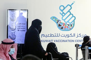A woman pushes another in a wheelchair as they queue to register before receiving a dose of Covid-19 coronavirus vaccine at the Kuwait International Fairground on February 1, 2021. AFP