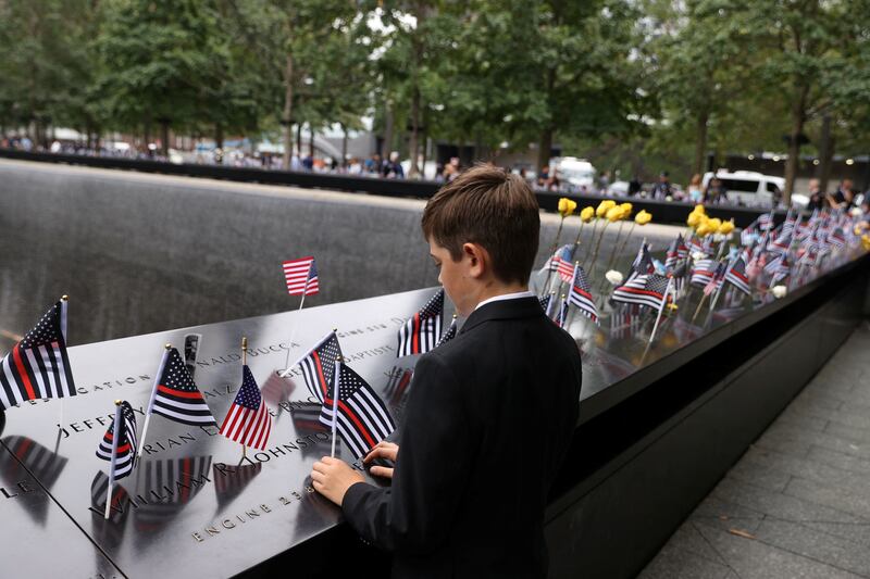A boy places a flag during a ceremony marking the 21st anniversary of the September 11, 2001 attacks in New York. Reuters