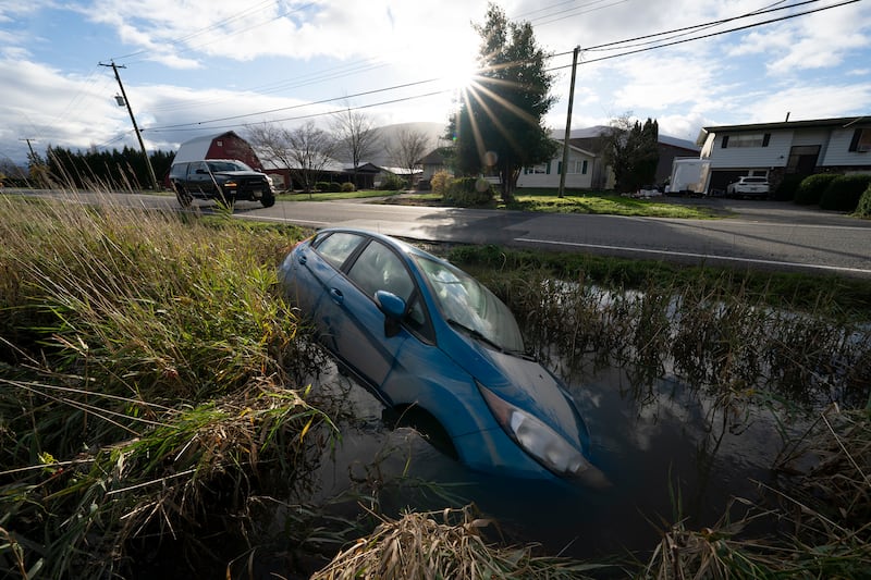 A car lies in a flooded ditch along a road in Chilliwack.