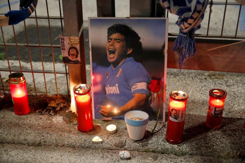 Candles are placed next to a picture of soccer legend Diego Maradona outside the San Paolo Stadium in Naples, Italy, Wednesday, Nov. 25, 2020. Diego Maradona has died. The Argentine soccer great was among the best players ever and who led his country to the 1986 World Cup title before later struggling with cocaine use and obesity. He was 60. (AP Photo/Alessandra Tarantino)